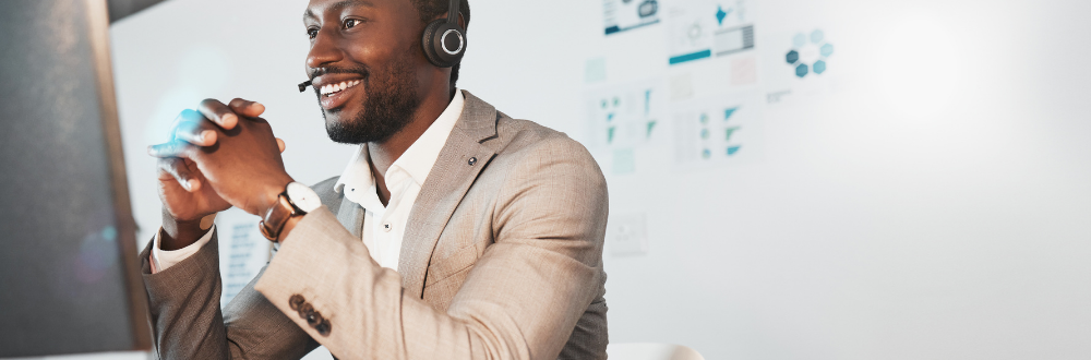 businessman sitting at desk with headset on conducting online meeting