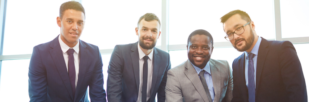 Group of businessmen in suits in front of bright window.
